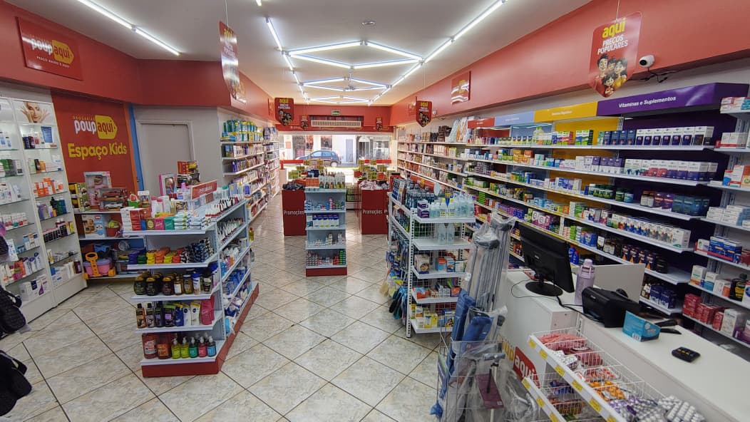 Área interna ampla da Drogaria Popaqui com gôndolas e atendimento.